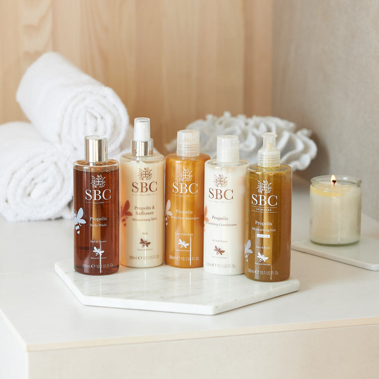 Propolis products on a marble tray in a bathroom with wooden features 
