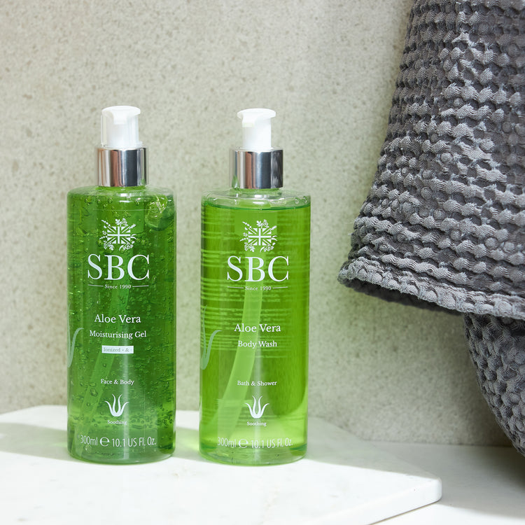 Aloe Vera Body Wash and Moisturising Gel on a marble tray in a stone bathroom with a grey towel