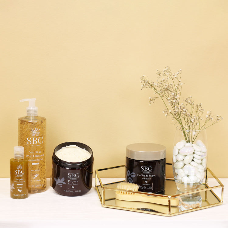 Vanilla, Propolis and Coffee Body products on a creamy yellow background with gold accessories 