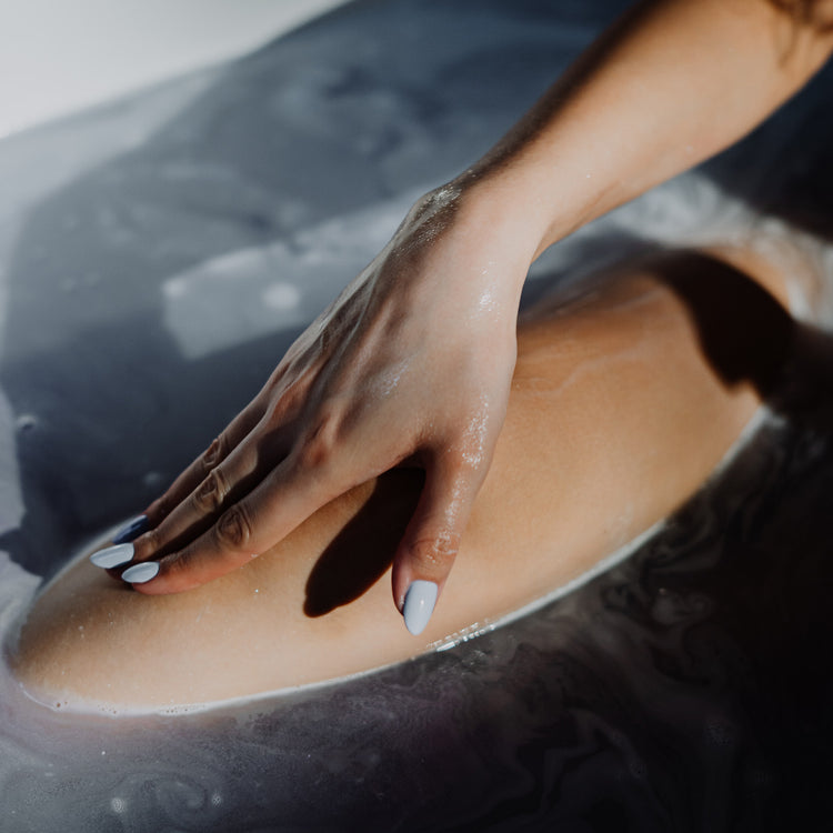 Womans hand in a bath with relaxing purple water