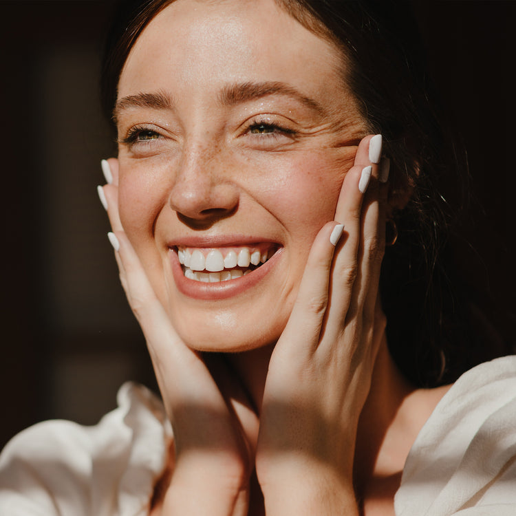 Woman Smiling Applying Skincare With Natural Light 