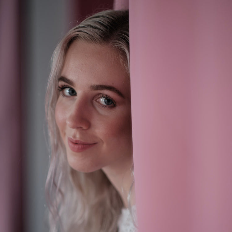 Woman Smiling behind pink curtain