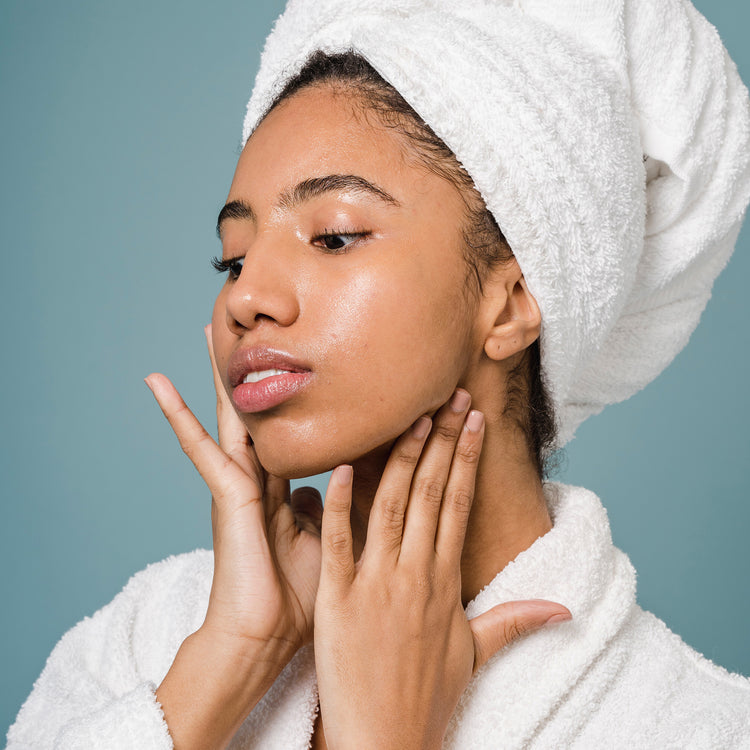 Woman in bath robe applying skincare to face 