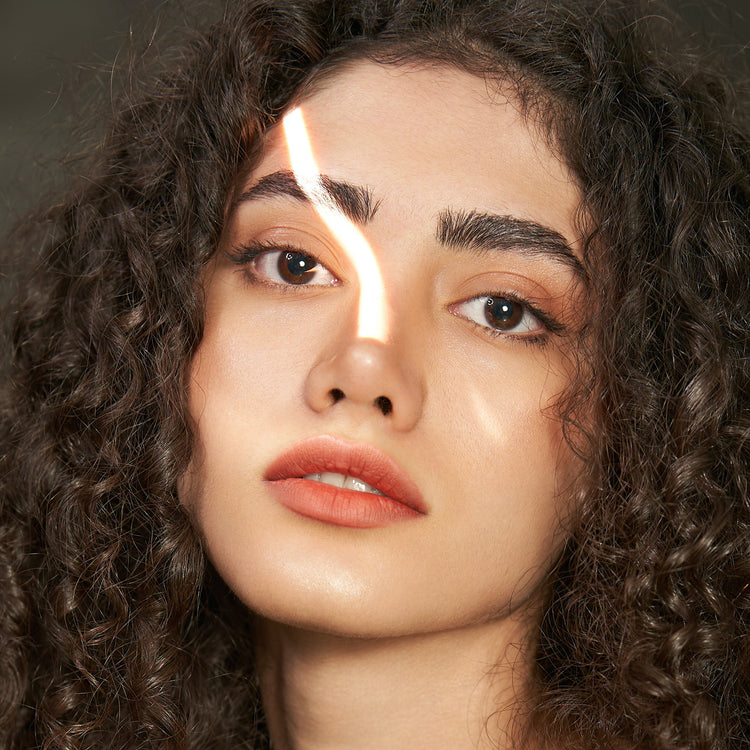 Woman looking at camera with natural light shining on face 