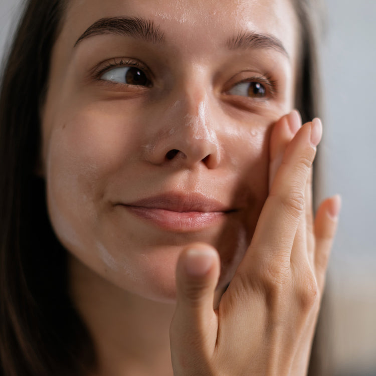 Woman with dewy skin applying skincare too cheek 
