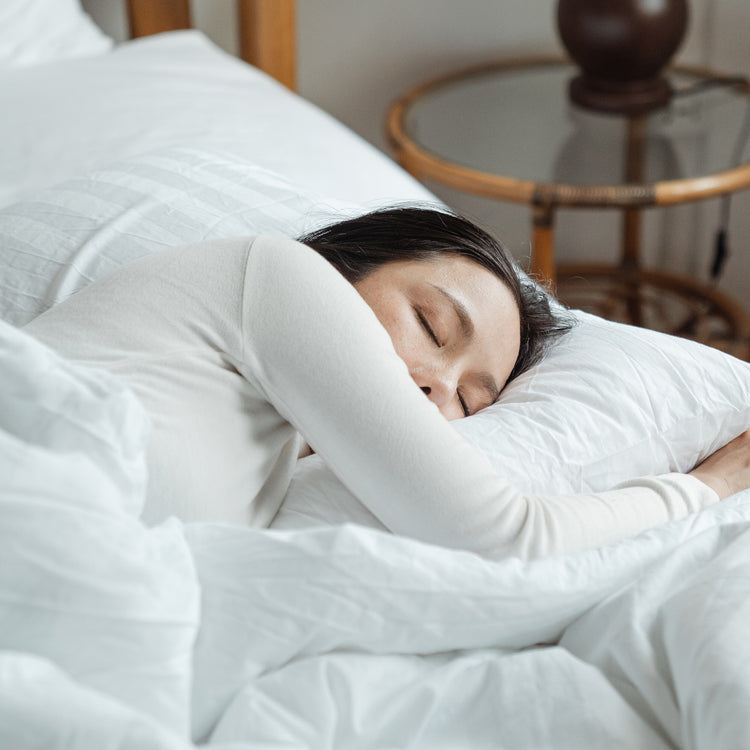 Woman sleeping in a bed with white sheets 
